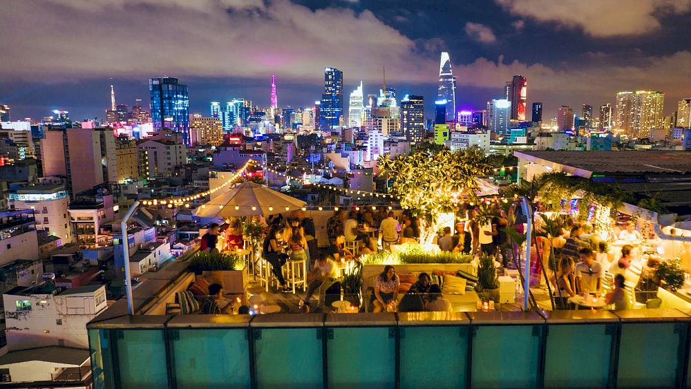 Open rooftop surrounded by greenery and neon lighting gives off a cheerful, modern vibe